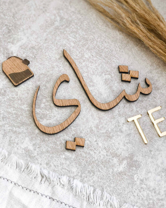 Dekorativt te-skilt med arabisk kalligrafi og teksten TE, fås i egefinér, valnødsfinér eller spejlakryl