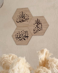 Tre dhikr rammer i egetræsfinér med arabisk kalligrafi på væg