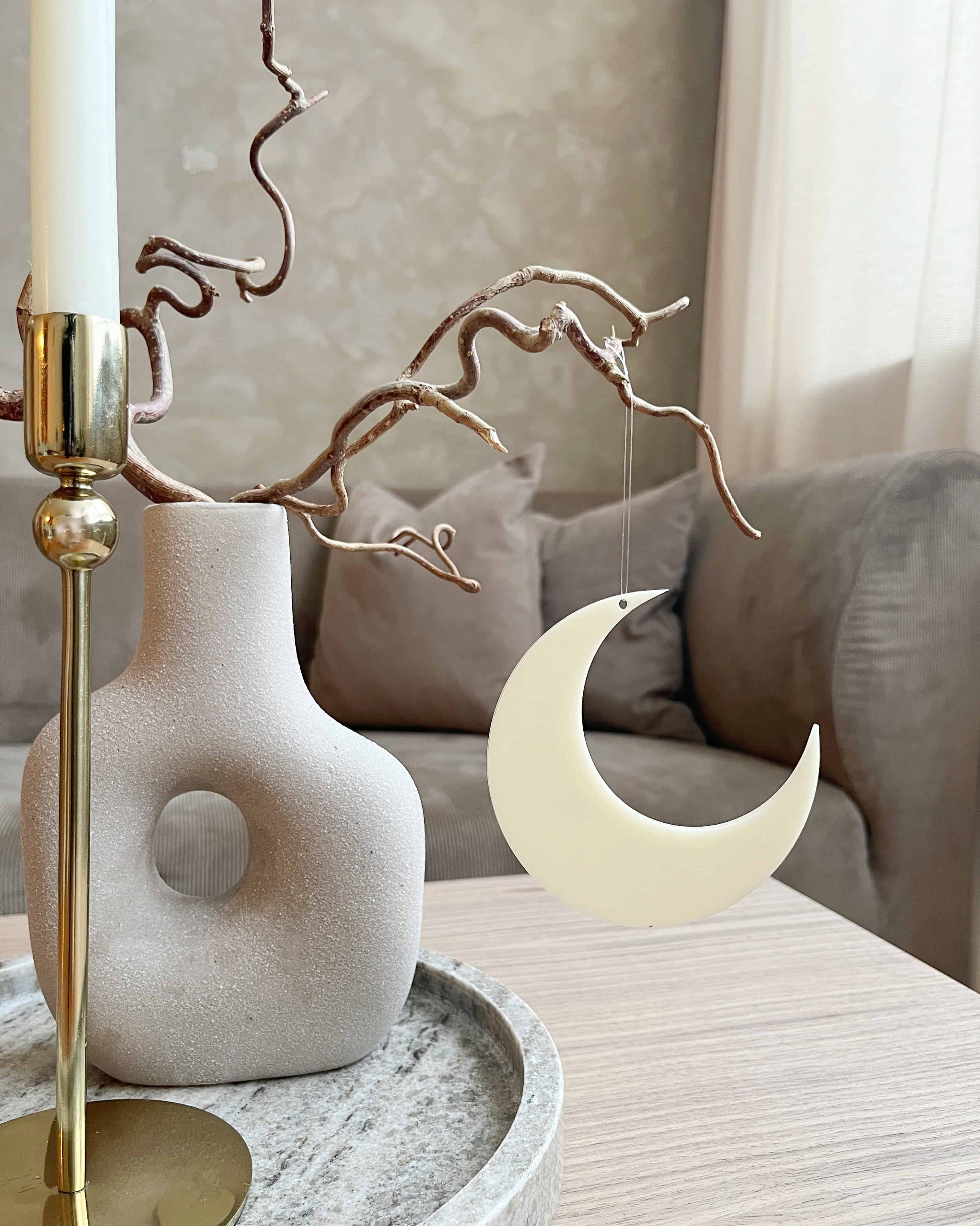 Minimalistisk måne i beige som hængende dekoration ved vase i stuen