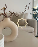 Minimalistisk stjerne i beige som hængende dekoration ved vase i stuen