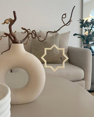 Minimalistisk stjerne i beige som hængende dekoration ved vase i stuen